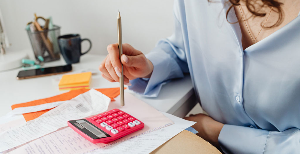 Des mains annotent un calendrier papier avec un stylo sur un bureau avec une tasse de café